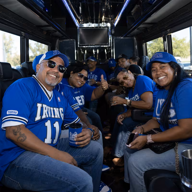 Group boarding a white charter bus for Sporting Event Transportation transportation in Irving